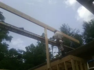 Carpenter setting a ridge beam over a new addition frame — Ice Dam Removal by Roofing Brothers in Pomona Park