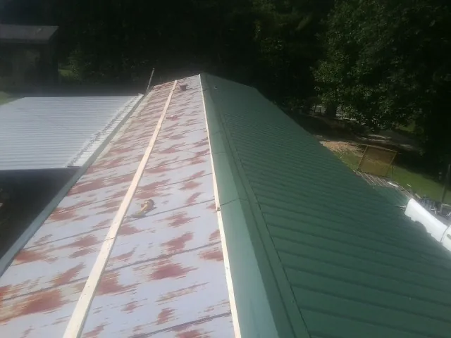 Old rusted panels beside newly installed green metal roofing — Wind Damage Roof Repair by Roofing Brothers in Pomona Park