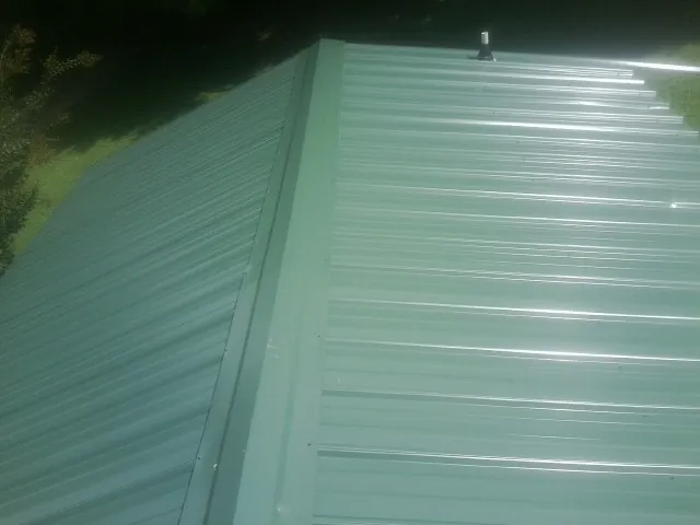 New green metal panels meeting at the ridge of a roof — Flat Roof Repair work by our crew in Pomona Park