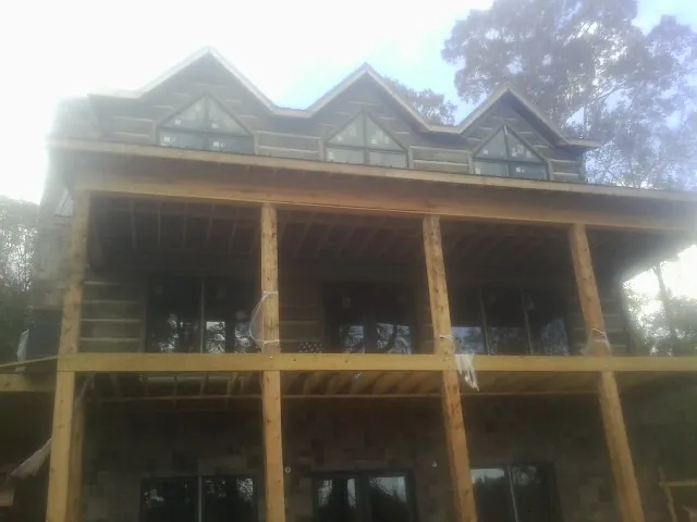 Dormers and porch framing on a large log home under construction — Roof Coating work by our crew in Pomona Park