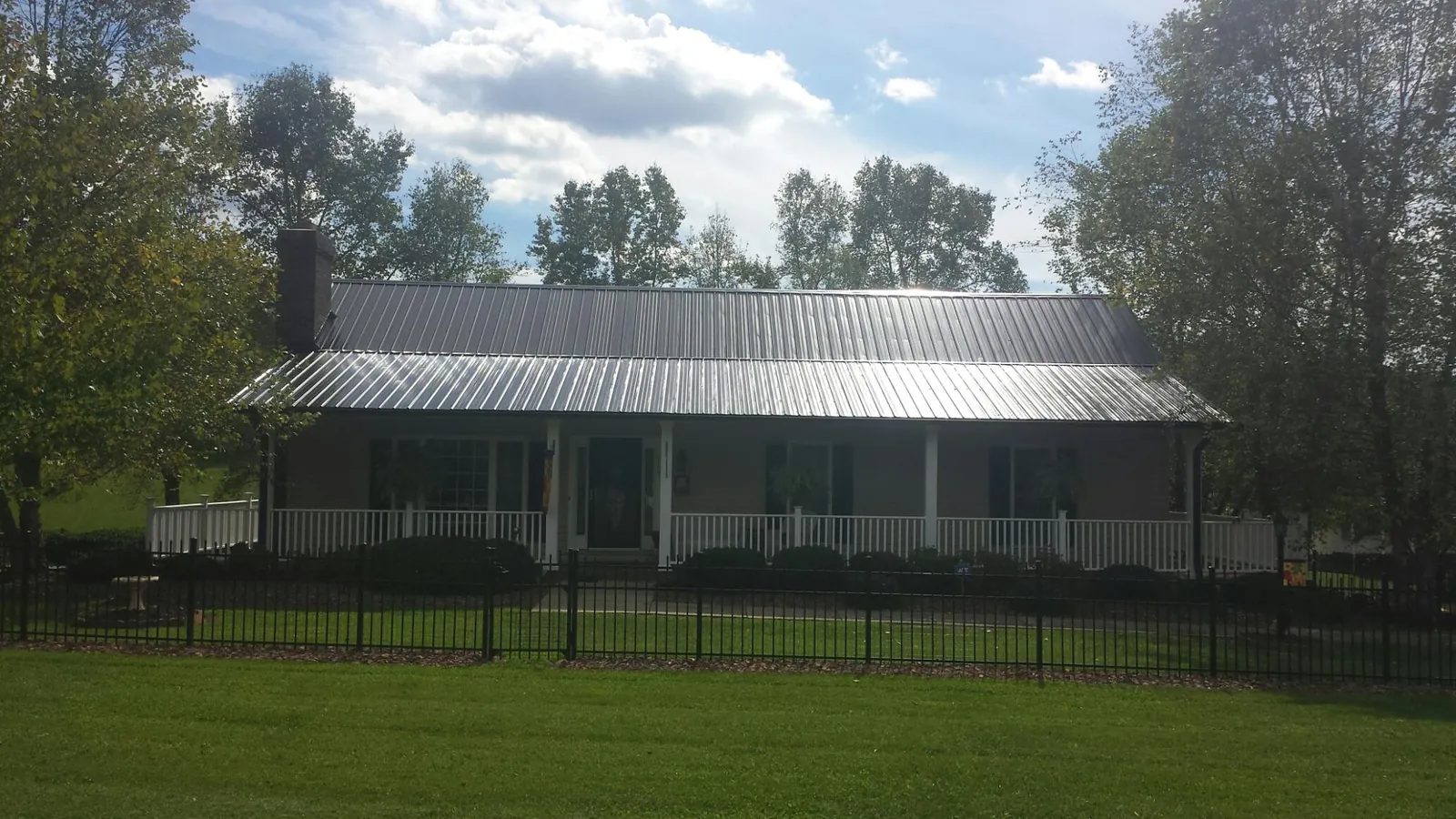Gray metal roof on a brick ranch with a full width front porch — Gutter Guard Installation work by our crew in Pomona Park
