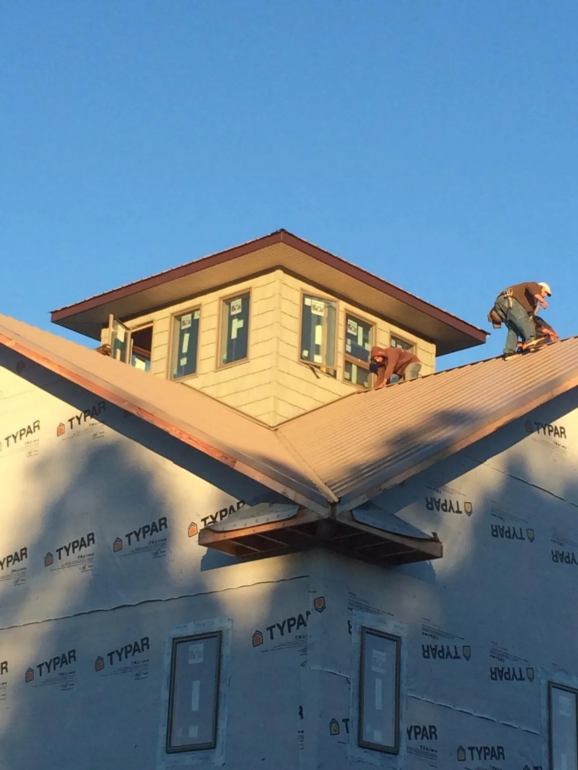 Roofers working around a rooftop cupola on a new metal roof at sunset — Roof Waterproofing in Pomona Park by Roofing Brothers